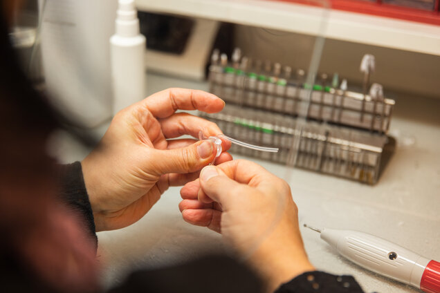 Die Hände einer Mitarbeiterin welche ein Hörgerät reparieren