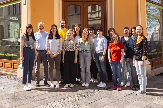 Gruppenbild aller Mitarbeiter von Hörgeräte Jens Steudler, die vor einer Filiale stehen