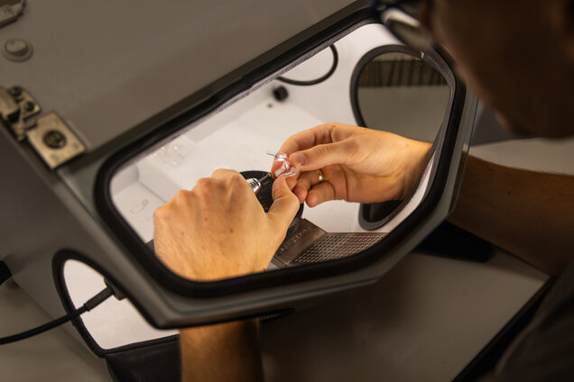 Die Hände einer Mitarbeiterin beim Zusammenbau eines Hörgerätes